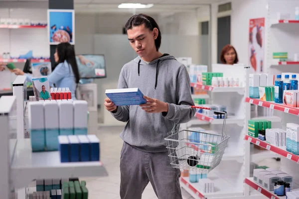 Hombre Joven Examinando Paquete Medicamentos Para Curar Enfermedades Mirando Los —  Fotos de Stock