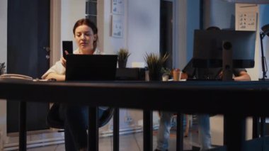 Akıllı telefonu kullanarak online görüntülü konuşma yapan kadın işçi, gece iş telekonferansı toplantısına katılıyor. Uzaktan kumandalı video konferansı için Compay raporu üzerinde çalışıyorum. El kamerasıyla..