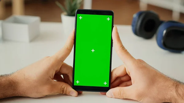 スマートフォンアプリで緑の画面表示を見ている男性のフリーランスは 隔離された背景とモックアップテンプレートを持つ電話を使用しています 空のクロマキーコピースペースを見てください 閉めろ 三脚ショット — ストック写真