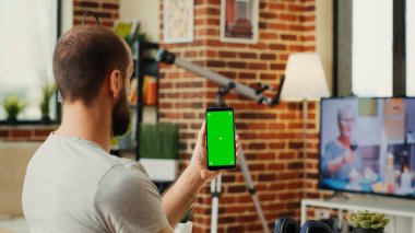 Ofis çalışanı yeşil ekran şablonu ile akıllı telefonu analiz ediyor, kroma anahtarı ve kopyalama alanı ile izole ekran kullanıyor. Kablosuz cep telefonunun boş model geçmişiyle çalışmak.