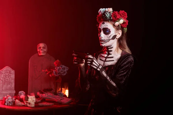 可怕的死亡女士在智能手机上拍照 用手机摄像头拍摄恐怖画面 头盖骨化妆的女人和站在演播室 神圣的音乐工作室之间的墨西哥光环 — 图库照片