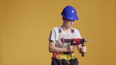 Çivi çakmak için elektrikli matkap tabancası kullanan becerikli bir kadın. İnşaat onarımı için elektrikli matkap makinesiyle çalışıyor. Stüdyoda mühendislik projesinin mimarisini yeniden inşa etmek.