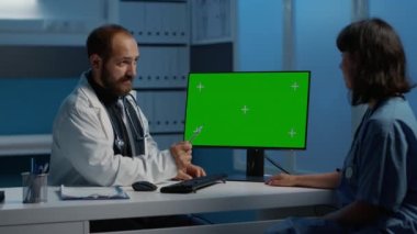 Sağlık ve hemşire hasta hastalıkları hakkında konuşuyor. İlaç tedavisi planlıyorlar. Doktor yeşil ekran krom anahtarını göstererek hastane ofisinde çalışırken bilgisayar şablonu oluşturur.