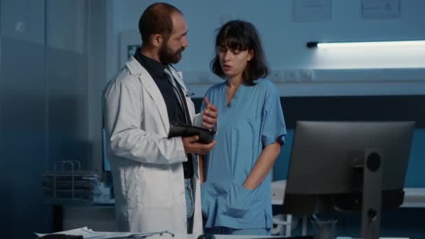 病院で何時間も働いている間 患者の病気の報告を調べるタブレットコンピュータの医療専門知識を見ている看護師と医師 医学の概念 — ストック動画