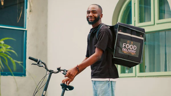 Afrikai Amerikai Fuvarozó Biciklizik Hogy Ételt Adjon Ügyfélnek Hátizsákot Cipelve — Stock Fotó