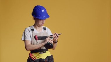 Elektrikli matkapla çalışan kadın inşaatçı ya da inşaat ve onarım için bir cihaz. Yenileme için çivi tabancası kullanmak alışılmadık bir durum..