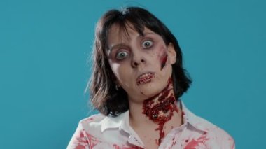 Undead zombie woman with bloody and deep wounds on neck prowling at camera. Terrifying evil looking brain dead monster smirking and growling at camera while covered in blood and flesh.