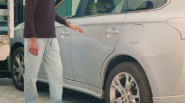 Yemek dağıtım işçisi, hazır yemek teslimatı için araçtan sırt çantasını alıyor. Restoran siparişini ön kapıdaki müşteriye vermek için arabayı terk ediyor. Paketi termal çantada getiren paket..