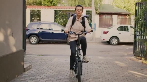 女信使来到顾客的前门 送午餐 骑自行车给顾客热背包里的外卖食品 骑自行车的女人 阳光灿烂的日子 — 图库视频影像