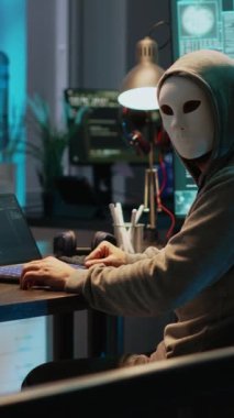 Dikey video: İsimsiz maske takan siber sahtekar güvenlik sistemini kırıyor, bilgisayar kötü amaçlı yazılım yaratmak ve çevrimiçi veri çalmak için virüs yüklüyor. Maskeli dolandırıcı ağ sunucusunu geç saatlerde hackledi