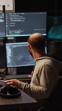 Dikey video: IT web geliştiricisi yeni sunucu arayüzü programlamak için pano kağıtlarındaki veri dosyalarını ve çoklu monitörleri karşılaştırıyor. Uçbirim penceresinde html betiği geliştiriliyor, kodlama veritabanı. El bilgisayarı