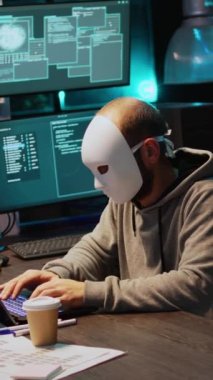 Dikey video: Maske takan siber sahtekar veritabanı sunucularını hackliyor, bilgisayar sistemine sızan ve kötü amaçlı yazılım yaratmak için virüsü etkinleştiren bilgisayar korsanı. Büyük verileri çalan gizemli sahtekar.