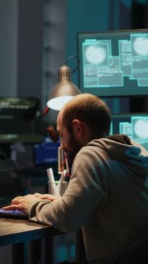 Dikey video: Genç mutlu bilgisayar korsanı kodlama başarısını gece kutluyor, hackleme sisteminden memnun. Gizli kimlikli gülümseyen bilişim programcısı başarı ve siber kazanç hakkında iyi hissediyor.