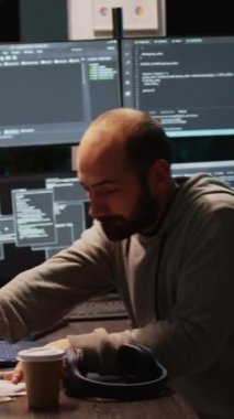 Dikey video: Genç programcı birden fazla monitörde sunucu kodu yazıyor, html dili ile terminal penceresini görüntülüyor. Sistem geliştirmek için dizüstü bilgisayardaki bulut bilgisayar arayüzü programlanıyor. El bilgisayarı