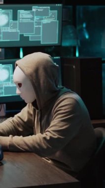 Dikey video: Geceleri bilgisayar sunucusunu maskeli bir şekilde hacklemek, bilgi çalmak için dizüstü bilgisayar ve birden fazla monitör üzerinde çalışmak. Gizli kimliği olan bir hacker tehlikeli davranıyor, bulut hesaplama