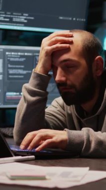 Dikey video: Yazılım mühendisi masada uyukluyor, yorgun düşüyor ve yeni arayüz programlama üzerinde çalışıyor. Gece yarısı sunucu kodu kullanarak kendini uykulu ve yorgun hisseden bir adam.