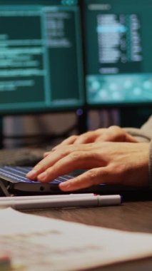 Dikey video: Genç hacker bilgisayardaki veritabanı sunucusuna giriyor, geliştirme amaçlı kötü amaçlı yazılım kullanarak sistemden büyük veriler çalıyor. Önemli bilgileri hacklemek için gece çoklu monitörlerle çalışmak