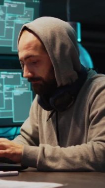 Dikey video: Erkek hackleme hırsızı güvenlik ihlali üzerinde çalışıyor, veri sunucusuna siber saldırı düzenliyor. Bilgisayar sistemi ve yazılımın hacklenmesi, veritabanı güvenliğini aşmak ve program bilgilerini çalmak
