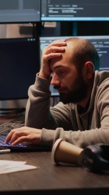 Dikey video: Erkek programcı ofis masasında uyuyakalıyor, yorgun hissediyor ve veritabanı sunucusunda çalışmaya çalışıyor. Yorgun ağ geliştirici gece geç saatte uykulu ve esniyor, bulut hesaplama.