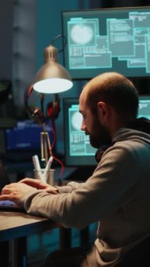 Dikey video: Bilgisayar kullanarak kurumsal veri sunucularına sızan ve baskı altında çalışan bir bilgisayar korsanı. Yazılım sistemine tehlikeli ağ virüsü bulaştırmak, güvenlik bilgilerini çalmak