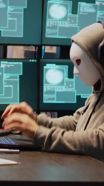 垂直视频 年轻的Pc小偷 带着面具 夜间侵入计算机服务器 在笔记本电脑和多个监视器上工作 窃取It信息或数据 隐藏身份的黑客 安全漏洞 — 图库视频影像
