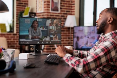 Erkek serbest çalışan, insanlarla iş görüşmesine katılan, evdeki bilgisayar ve web kamerasını kullanan. Uzaktan kumandalı telekonferans görüşmesinde çalışıyor, uzaktan görüntülü konferans sohbetinde konuşuyor..