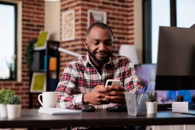 Ofis çalışanı akıllı telefondan internet taraması yapıyor, iş yerinde internet uygulaması ve sosyal medya ağı kullanıyor. Cep telefonuyla uzaktan çalışmak, web sitesinde çevrimiçi mesajlaşmak.