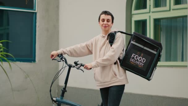 年轻的快递员负责运送食物 骑自行车 背着装食物的背包 快递服务员工递送快餐店餐单 阳光明媚 — 图库视频影像