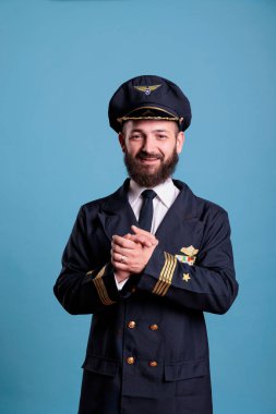 Gülümseyen, heyecanlı, profesyonel üniformalı pilot el çırpıyor. Mutlu olumlu uçak kaptanı alkışlıyor, avuç içlerini sallıyor, ayakta duruyor, kameraya bakıyor, orta ölçekli stüdyo çekimi yapıyor.