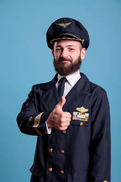 プロの制服の肖像画 カメラを見て飛行機のパイロットを着て親指のジェスチャーを示す笑顔飛行機のアビエイター 指で承認サインを示すアビエイター スタジオ中出し — ストック写真