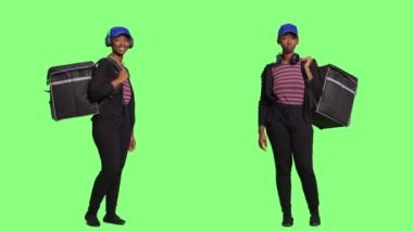 Afrika kökenli Amerikalı kadın kurye termal sırt çantası taşıyor ve yeşil ekranda yemek dağıtıyor. Fast food siparişini çantada tutan kadın, tüm vücudu yeşil ekran..