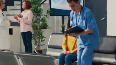 Asyalı hastaya röntgen sonuçlarını gösteren tıbbi asistan, hastalık teşhisini ve sağlık tedavisini açıklıyor. Sağlık merkezindeki ortopedi konsültasyonunda radyografi taraması analiz ediliyor.