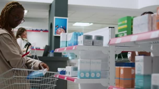 아시아 용인들은 약국에서 일하면서 고객들에게 선반에 비타민 상자를 분석하여 사람들을 — 비디오