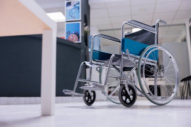 Klinikteki boş resepsiyon masasının önünde ameliyat edilmemiş bir tekerlekli sandalye. Hastanenin önündeki kullanılmayan tıbbi ekipman. Hasta ya da doktor yok..