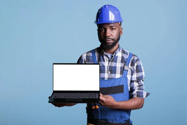 한건축가는 광고를 화면으로 랩탑을 카메라를 봅니다 아프리카 미국인 노동자 파란색 — 스톡 사진