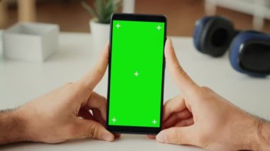 Akıllı telefon uygulamasında yeşil ekran görüntüsüne bakan serbest çalışan bir erkek, izole edilmiş arka plan ve model şablonu kullanarak telefon kullanıyor. Boş krom anahtar kopyalama alanına bakıyorum. Kapatın. Üçayak atışı.