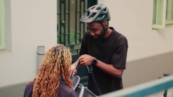 快递餐厅送餐服务由快递员在前门送餐 为顾客提供纸袋餐 非洲裔美国人客户将快餐外卖套餐打包 骑自行车运送 — 图库视频影像