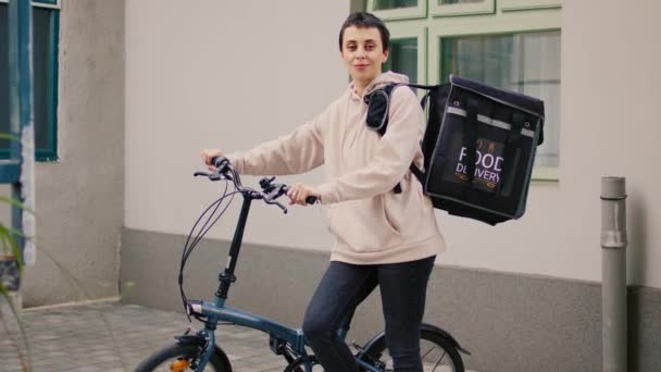 快乐的女性食品快递员坐在前门送餐 午餐时背着背包 送货员用热袋和骑自行车运送快餐 — 图库视频影像