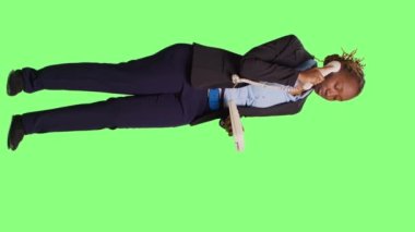 Dikey video: Şirket çalışanı stüdyoda sabit telefon görüşmesi yapıyor, ofis telefonuna kablosuyla cevap veriyor. İş kadını geçmişinden dostane davranıyor..