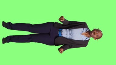 Dikey video: Kızgın üzgün kadın yeşil perde arka planında takım elbise giyiyor, iş kadını agresif davranıyor ve stüdyoda çığlık atıyor. Negatif sinir bozucu şirket yöneticisi ofiste çalışıyor.