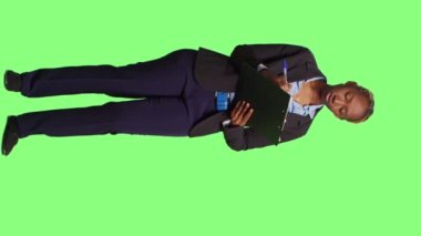 Dikey video: İş muhasebecisi yeşil ekran arkaplanı üzerine notlar alıyor, bilgi ve şirket verilerini pano kağıtlarına yazıyor. Yönetici olarak çalışan tam vücut yeşil ekran.