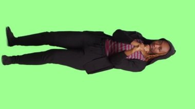 Dikey video: Yeşil ekranda yumruklarını sıkan agresif negatif kız, tüm vücudu yeşil ekran arka planında duruyor. Öfkeli davranan ve kavga etmek isteyen bir kadın.