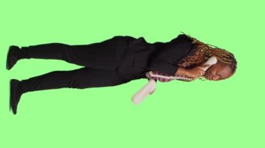 Dikey video: Neşeli insan yeşil ekran arkaplanı üzerinde tüm vücuduyla ev telefonu kullanıyor, yeşil ekran arkaplanı üzerinde duruyor. Kabloyla ofis telefonunda sohbet etmek, arkadaşça davranmak ve...