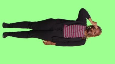 Dikey video: Baş ağrısı ve iyi olmamakla uğraşan, tüm vücudun yeşil perde arkaplanı üzerinde ağrılı migrenden muzdarip hasta genç bir yetişkin. Şakakları ovalayarak mutsuz davranan endişeli insan..