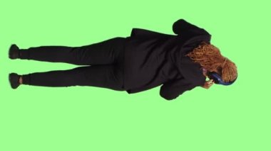 Dikey video: Mutlu kadın model kulaklıkla müzik dinliyor, tüm vücudu yeşil ekranda duruyor. Kablosuz kulaklıklarda radyo şarkıları ve seslerinin tadını çıkarmak, eğlenmek..