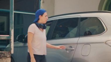 Kadın teslimatçı, yemek teslimatı yapmak için arabadan müşteriye yemek siparişi veriyor. Fast food paket servisini araçtan alıp, restoran taşıyıcısı olarak çalışmak..