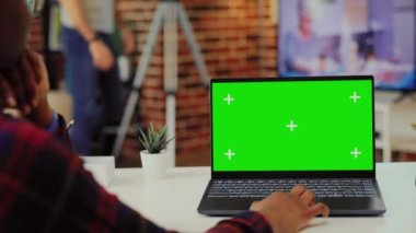 Afrika kökenli Amerikalı bir kadın masadaki dizüstü bilgisayara bakıyor, kablosuz bilgisayardaki izole görüntü ve model şablonuyla çalışıyor. Boş telif alanı olan taşınabilir bilgisayar kullanılıyor.