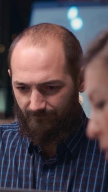 Dikey video: Çalışan iş toplantısında kameraya bakıyor, gülümsüyor, yönetim kurulunda iş arkadaşları konuşuyor, yavaş çekim. Beyin fırtınası yapan meslektaşlar, birlikte çalışan şirket çalışanı. Yakın plan.