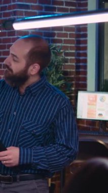 Dikey video: İş analizi ekibi toplantısı, proje yöneticisi kurumsal sunum gösteriyor, pazarlama stratejisi planlıyor. Satış istatistiklerini izleyen iş arkadaşları dijital panodan uzaklaşsın