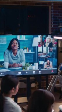 Dikey video: Uzaktan kumandalı ekip görüntülü arama toplantısına katılıyor, iş arkadaşları gece video konferansında konuşuyor. Çeşitli insanlar telekonferansta sohbet ediyor, iş arkadaşları video konferansında fikir alışverişinde bulunuyor.